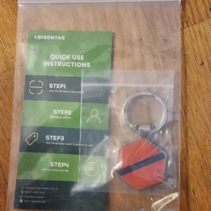 Röd nyckelring/ pet tag med svart rand från Disontag - Säljer en sexkantig nyckelring / pet tag i rött med en svart diagonal rand. Nyckelringen har en QR-kod på baksidan och levereras i en plastpåse med instruktioner. Perfekt som accessoar till dina nycklar.
