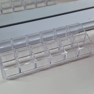 Transparent sminkförvaring i akryl - Praktisk och stilren sminkförvaring i transparent akryl med flera fack, perfekt för att organisera läppstift eller andra sminkprodukter på sminkbordet.