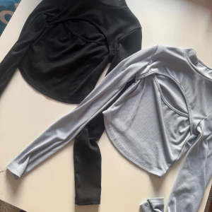 Blå och svart långärmad croppad topp - Två långärmade croppade toppar i blå och svart med unik cut-out detalj över bröstet. 