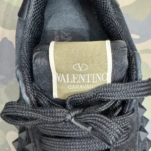 Svarta sneakers från Valentino Garavani - Snygga svarta sneakers från Valentino Garavani med coola nitar på sidorna. Skorna har en klassisk snörning och en kontrasterande beige sula. Perfekta för att ge din outfit en edgy touch. Box följer med vid köp