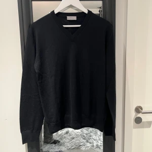 Svart kashmirtröja från Max Tonso - Säljer en elegant svart kashmirtröja från Max Tonso. Tröjan har en v-ringad design och långa ärmar, perfekt för en stilren look. Den är mjuk och bekväm. Passar både till vardags och mer uppklädda tillfällen.