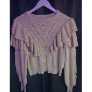 Beige stickad tröja med volangdetaljer - Säljer en söt beige stickad tröja med volangdetaljer från ONLY i storlek S. Tröjan har ett fint stickat mönster och långa ärmar. Använd några fåtal gånger men säljs för den inte kommer till användning längre. Nypris 559kr