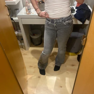 Grå jeansbyxor - Snygga grå jeansbyxor med en klassisk bootcut-stil. De har en bekväm passform och är perfekta för en avslappnad look. Byxorna har fickor både fram och bak samt en dragkedja och knapp framtill.