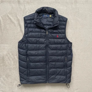 Ralph Lauren - Snygg svart dunväst från Ralph Lauren Storlek S den är i nyskick förutom hålet som är lagt som ni ser på sista bilden hålet syns inte när man har på sig den 