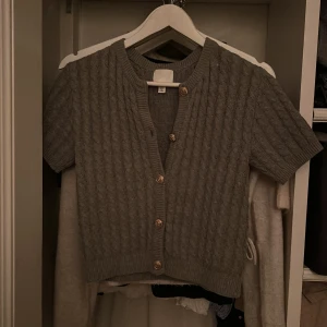 Grå kofta från H&M - Säljer en stilren grå kofta från H&M med korta ärmar och knappar framtill. Jättebra skick och skulle säga att den är som ny! Säljer för 170kr då den inte kommer till användning🥰