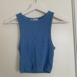 Blå och svart ribbad linnetopp från Zara - Säljer två ribbade linnetoppar från Zara i blått och svart. Perfekta för sommaren med en croppad passform och ärmlös design. Superbekväma och lätta att matcha med olika outfits. Den blå är lite urtvättat i färgen annars bra skick. Lite noppriga kn de vara. 