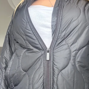 Svart quiltad jacka - Säljer en svart quiltad jacka med dragkedja. Jackan har en normal passform och långa armar! Hos mig kom den inte till användning, den har endast använts fåtal gånger!