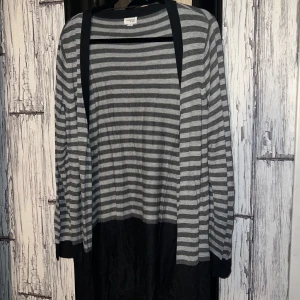 Grå och svart randig kofta från Generous by Lindex - Säljer en mysig grå och svart randig kofta från Generous by Lindex. Koftan har långa ärmar och en öppen design utan knappar. Perfekt för lager-på-lager under kyligare dagar.