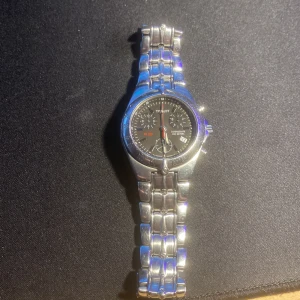 Tissot PR 200 klocka i silver - Säljer en stilren Tissot PR 200 klocka med silverfärgad länkarmband och svart urtavla. Klockan har tre sub-dials och datumvisning. Perfekt för den som söker en klassisk och tidlös design.