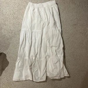 Vit långkjol från Lindex - Säljer en vit långkjol från Lindex med elastisk midja! Kjolen har en luftig och bekväm passform med flera lager som ger en fin volangeffekt. Perfekt för varma dagar eller sommaren!❣️❣️😍😍
