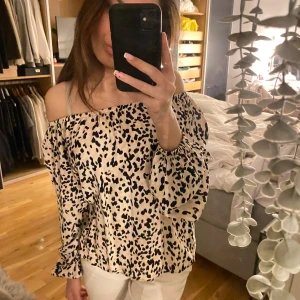 Leopardmönstrad offshoulder blus - Gina Tricot - Säljer en snygg leopardmönstrad offshoulder blus från Gina Tricot. Blusen är långärmad och lös passformen, perfekt för en snygg look. Den är i en beige och har leopardtryck på sig. Passar perfekt till både jeans och kjol!