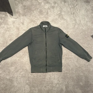 Grön tröja med dragkedja från Stone Island - Säljer en stilren grön tröja från Stone Island med dragkedja och hög krage i storlek S. Nypris på cirka 4500kr