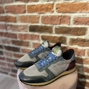 Valentino rockrunners  - Snygga Valentino sneakers med en mix av grått och blått. Skorna har en klassisk design med snörning och en bekväm sula. Perfekta för en stilren look.
