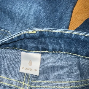 Blå jeans från Dondup - Snygga blå jeans från Dondup med klassisk femficksdesign och en läderpatch med logga baktill. Jeansen har en stilren look med ljusa sömmar och knappgylf.