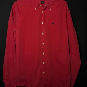 Morris Långärmad Skjorta | Röd | Regular/Slim | Stl M - Läs nedan för mer info!😊  Snygg röd skjorta från Morris med klassisk krage och knappar framtill. Skjortan har en diskret broderad detalj på bröstet i mörkblått. Perfekt för en stilren look.  Produktinformation:  ✅ Märke: Morris ✅ Storlek: M  ✅ Färg: Röd ✅ Material: Bomull ✅ Passform: Regular/Slim – perfekt att styla med jeans/kostymbyxor/chinos. ✅ Skick: Bra skick, inga skador eller defekter  Frakt och betalning: 📦 Snabb leverans – skickar inom 1-2 dagar 📦