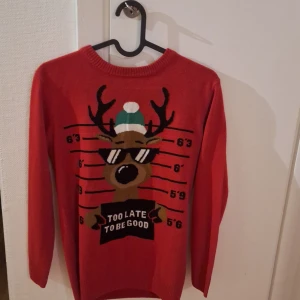 Röd jultröja med renmotiv - Rolig röd jultröja med ett renmotiv som bär solglasögon och texten 'Too Late To Be Good'. Är i storlek 152 men har XS och kan ha den. Säljer då jag har andra och denna har ej kommit till användning