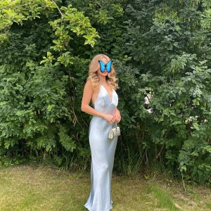 En ljusblå klänning från Bec and bridge  - Elegant ljusblå långklänning i siden med djup v-ringning och smala axelband. Perfekt för sommarens festligheter.