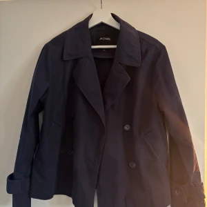 Mörkblå kappa från Monki - Marinblå trenchcoat från Monki. Använd fåtal gånger, säljer då den inte kommer till användning 