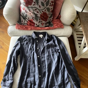 Blå linne skjorta från H&M - Snygg blå linne skjorta från H&M i regular fit. Skjortan har långa ärmar och knappar framtill. Perfekt för en stilren look.