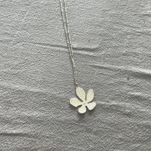 Silverfärgat halsband med blomma - Elegant silverfärgat halsband med ett hängsmycke i form av en blomma. Blomman har ett intrikat mönster och en liten pärla i mitten. Perfekt för att lägga till en touch av elegans till din outfit. Själva halsbandet är lite långt! 🤍🤍🤍💕💕💕