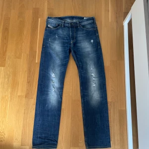 Blå jeans från Diesel - Snygga blå jeans från Diesel med slitna detaljer och en klassisk femficksdesign. Jeansen har en straight passform. 