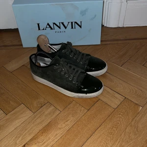 Gröna sneakers från Lanvin - Snygga Gröna  sneakers från Lanvin med mocka. Skorna är använda men är fortfarande i bra skick Perfekta för en stilren look. Lite slitningar som man ser på bilden men annars är helheten bra låda och allt följs med 