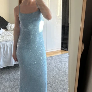 Ljusblå glittrig långklänning - Säljer en fantastisk ljusblå långklänning med glittriga paljetter. Klänningen har smala axelband och går att knyta på olika sätt i ryggen. Aldrig använts🩵Jag är 161 och klänningen släpar i marken. 