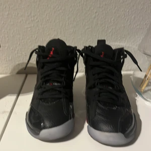 Svarta Nike Air Jordans - Snygga svarta Nike Air Jordans med hög design och snörning. Skorna har en rund tå och en kontrasterande vit sula. Perfekta för dig som vill ha en stilren look med en sportig touch.