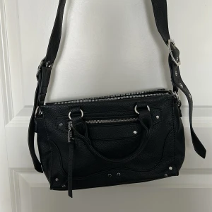 Svart axelväska från Misako - Snygg svart axelväska från Misako med justerbar axelrem och praktiska handtag. Väskan har flera dragkedjor. Aldrig använd 