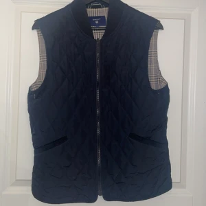 Blå quiltad från GANT - Snygg blå quiltad väst från GANT  med dragkedja och rutigt foder. Perfekt inför våren och sommaren, skick 8/10. Pris är inte hugget i sten och skriv vid minsta lilla fundering