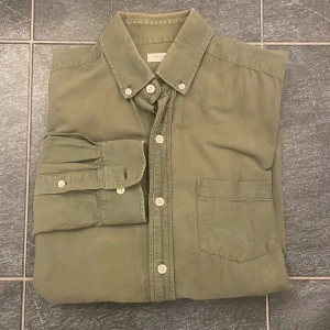 Olivgrön skjorta från A DAY’S MARCH - En riktigt fräsch skjorta från A DAY’S MARCH. Skicket är 10/10 Inga defekter alls. Skjortan är i Storlek M. Skriv till mig under minsta fundering, skickar flera bilder på skjortan om ni skriver! Pris är heller inte hugget i sten