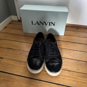 Lanvin skor  - Snygga marinblå sneakers från Lanvin med snörning och rund tå. Skorna har en stilren design med en vit sula som kontrasterar mot det marinblåa materialet. Perfekta för en casual look. Box och extra snören ingår vid köp! Vid frågor är det bara att höra av sig! 