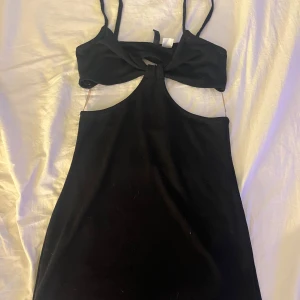 Svart klänning från Divided - Snygg svart klänning från Divided med en unik design. Klänningen har smala axelband och en öppen ryggdetalj. Perfekt för en kväll ute eller en speciell tillställning. Skriv gärna vid frågor eller fler bilder🤍