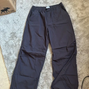 Svarta parachute byxor från Zara - Säljer också ett par svarta parachute pants från Zara med elastisk midja och avslappnad passform. Byxorna har en enkel design utan mönster och är tillverkade i ett luftigt material.