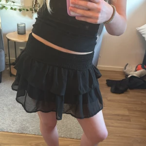 Svart volangkjol - Säljer en söt svart kortkjol med volanger. Kjolen har en elastisk midja som ger en bekväm passform. Skriv för frågor ❤️