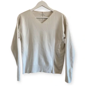 Vit v-ringad tröja från Day Birger et Mikkelsen - Säljer en stilren grå-vit-ish tröja från Day Birger et Mikkelsen. Tröjan har en v-ringad design och långa ärmar, perfekt för en elegant look. Tillverkad i ett mjukt material med ribbade detaljer vid nederkanten. Bra skick, slitage på tyg efter tvätt finns.