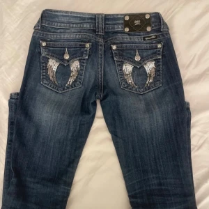 Lågmidjade miss me jeans - Snygga blå jeans från Miss Me med unika broderade fickor med vingmotiv och glittriga detaljer. Jeansen har en låg midja och en tight passform som framhäver. Storlek 27 - finns även på vinted Vanna.malama