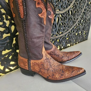 Old gringo Bruna cowboy boots med blommigt mönster - Snygga cowboy boots i brunt skinn med detaljerade blommiga mönster. Stövlarna har en spetsig tå och dekorativa broderier längs skaftet. Perfekta för en unik stil.                    Nytt pris var runt 12.000 kr. Använda endast 1 gg