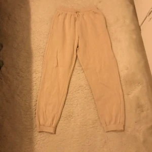 Beige mjukisbyxor - Säljer ett par bekväma beige mjukisbyxor med resår i midjan och vid bensluten. Perfekta för en avslappnad dag hemma eller en promenad i parken.