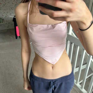 Rosa topp med snörning - Säljer en söt rosa linnetopp med smala axelband och snygg snörning i ryggen. Perfekt för sommarens varma dagar. Toppen har en stilren och elegant design som passar till många olika outfits.