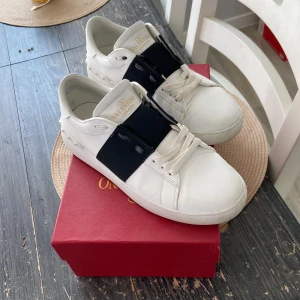 Valentino open - Snygga vita Valentino Garavani sneakers med svart detalj över snörningen. Skorna har en rund tå och är tillverkade i skinn. Perfekta för en stilren look.