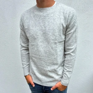 Kashmir tröja - 100 % Kashmir . Storlek M . Helt Ny. Modellen är 177 cm lång! 🌟Snygg ljusgrå stickad tröja med rund hals och långa ärmar. Tröjan har en enkel och clean look, perfekt till jeans eller chinos. Mjuk och skön känsla tack vare det stickade materialet. Passar dig som gillar stilrena och tidlösa plagg.