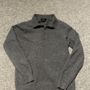 Grå polotröja i ull/kashmir Massimo Dutti - Mörkgrå polotröja från Massimo Dutti i en lyxig mix av ull och kashmir. Tröjan har klassisk krage med knappar och lång ärm, perfekt för dig som gillar stilren och tidlös look. Supermjuk och skön att bära under kyliga dagar. Är strl m men skulle säga s/xs väldigt bra skick 