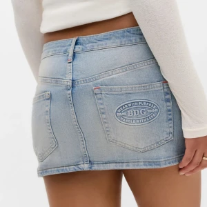 Lågmidjad  jeanskjol - Snygg ljusblå jeanskjol från BDG. Aldrig använd med lapparna kvar. 