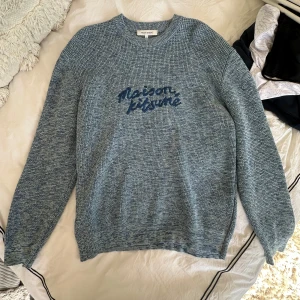 Blå stickad tröja Maison Kitsuné - Säljer en blåmelerad stickad tröja från Maison Kitsuné i storlek M. Tröjan har rund hals, lång ärm och ett snyggt Maison Kitsuné-tryck framtill. Materialet är mjukt och stickat, perfekt för dig som gillar chill och stilren vibe.