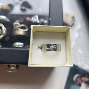 Bred silverring med ödlemotiv - Cool bred ring i silverfärgad metall med ett utskuret ödlemotiv runt om. Ringen har en blank finish och är i storlek 17. Perfekt för dig som gillar unika detaljer och djurinspirerade accessoarer. Rostfritt stål, 17.3 mm