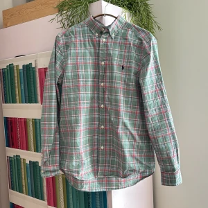 Rutig grön skjorta från Ralph Lauren S/XS - Säljer en klassisk rutig skjorta från Ralph Lauren i grönt, rött och vitt. Skjortan har lång ärm, knappar hela vägen och den ikoniska broderade loggan på bröstet. Skriv vid minsta fundering.