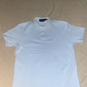 Ljusblå Polo Ralph Lauren piké - Snygg ljusblå pikétröja från Polo Ralph Lauren med klassisk krage, korta ärmar och broderad logga på bröstet. Modellen är slim fit och tillverkad i bomull för en fräsch och stilren look.