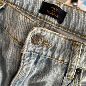Ljusblå raka jeans från NLY Jeans - Säljer ett par ljusblå jeans från NLY Jeans med klassisk femficksdesign och raka ben. Jeansen har hög midja och är tillverkade i bomull med snygga kontrastsömmar. Perfekta för en avslappnad och trendig look. Helt oanvända, därav ny skick! 