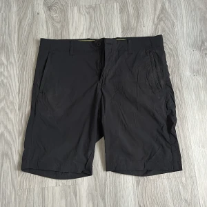 Svarta shorts Sail Racing i polyester - Svarta shorts från Sail Racing i lätt och smidigt polyestermaterial. Klassisk design med bälteshällor, knapp och dragkedja framtill samt fickor på sidorna och bak. Perfekta för sommardagar när du vill ha en clean och sportig look.